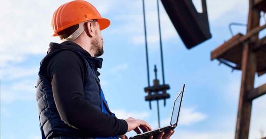 A man working in an oil field looking at a rig