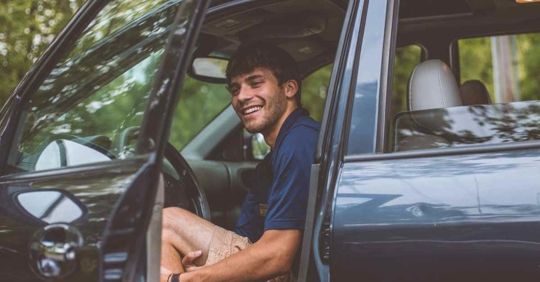 A young man in the driver's seat of a car