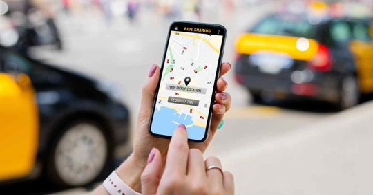 A person's hand holding a phone that displays a ridesharing app