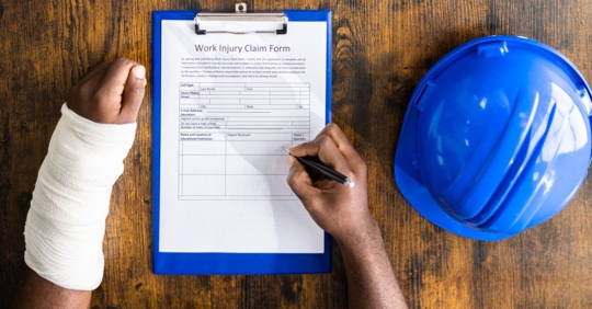man in cast filling out workers' compensation form